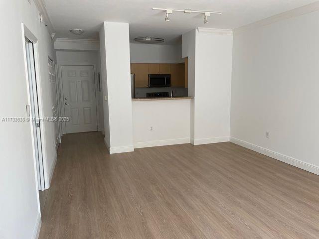 unfurnished living room with ornamental molding and light wood-type flooring