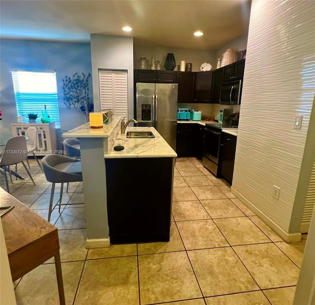 kitchen with light tile patterned floors, a kitchen bar, sink, and appliances with stainless steel finishes