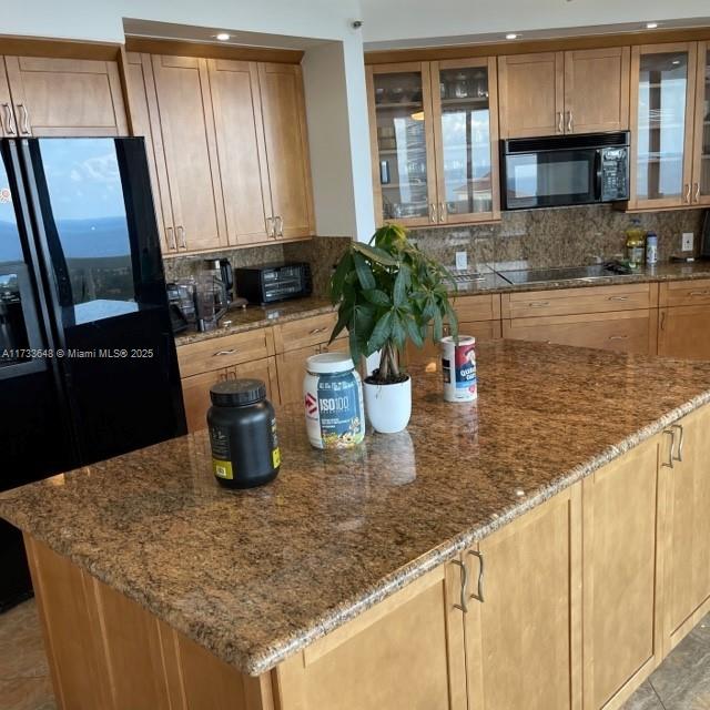 kitchen featuring light stone counters, decorative backsplash, and black appliances