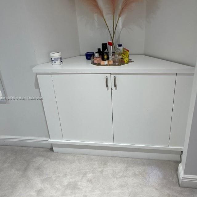 bar featuring light colored carpet and white cabinets