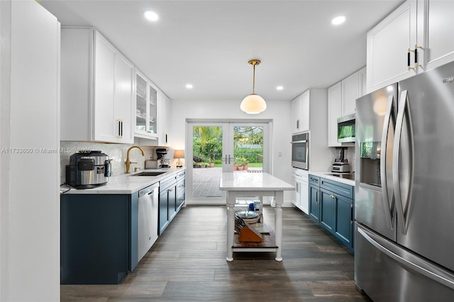 kitchen with blue cabinetry, stainless steel appliances, decorative light fixtures, and white cabinets