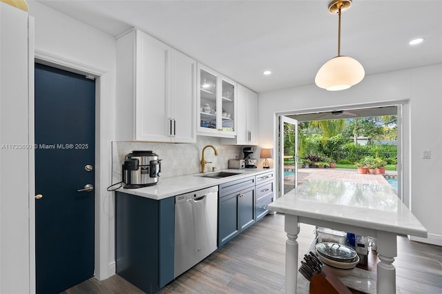 kitchen featuring pendant lighting, sink, dishwasher, white cabinetry, and decorative backsplash