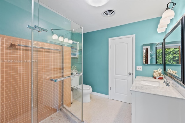 bathroom featuring vanity, toilet, and a shower with door