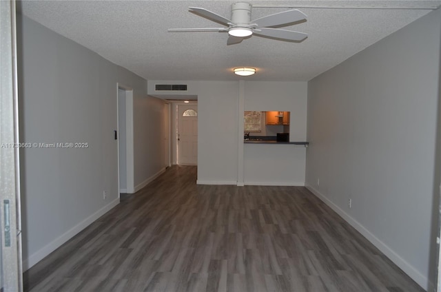 empty room with ceiling fan, dark hardwood / wood-style floors, and a textured ceiling