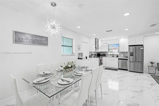 dining room featuring an inviting chandelier, plenty of natural light, sink, and a textured ceiling