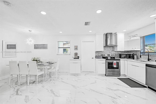 kitchen featuring pendant lighting, white cabinetry, wall chimney exhaust hood, and appliances with stainless steel finishes