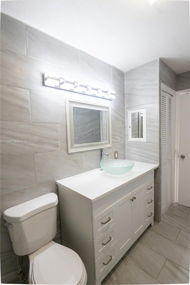 bathroom featuring vanity, tile walls, tile patterned floors, and toilet