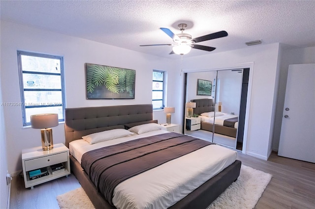 bedroom featuring hardwood / wood-style flooring, ceiling fan, a closet, and a textured ceiling