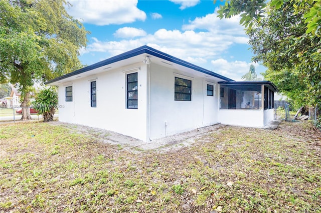 view of home's exterior with a sunroom and a yard