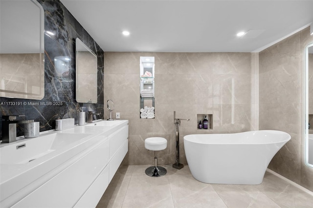 bathroom with tile walls, a bath, vanity, and tile patterned floors