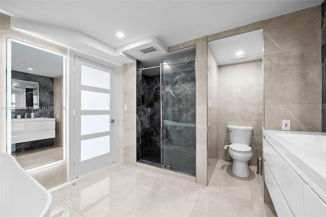 bathroom with a shower with door, vanity, tile walls, and toilet