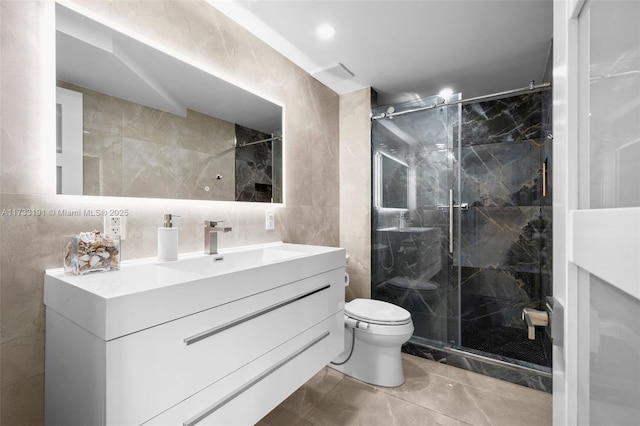 bathroom featuring a shower with door, vanity, tile walls, and toilet