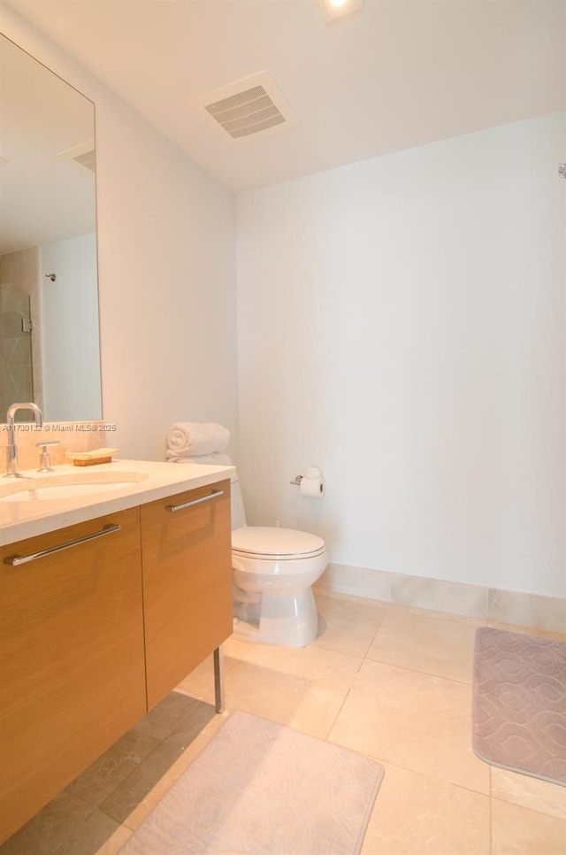 bathroom with vanity, a tile shower, tile patterned floors, and toilet