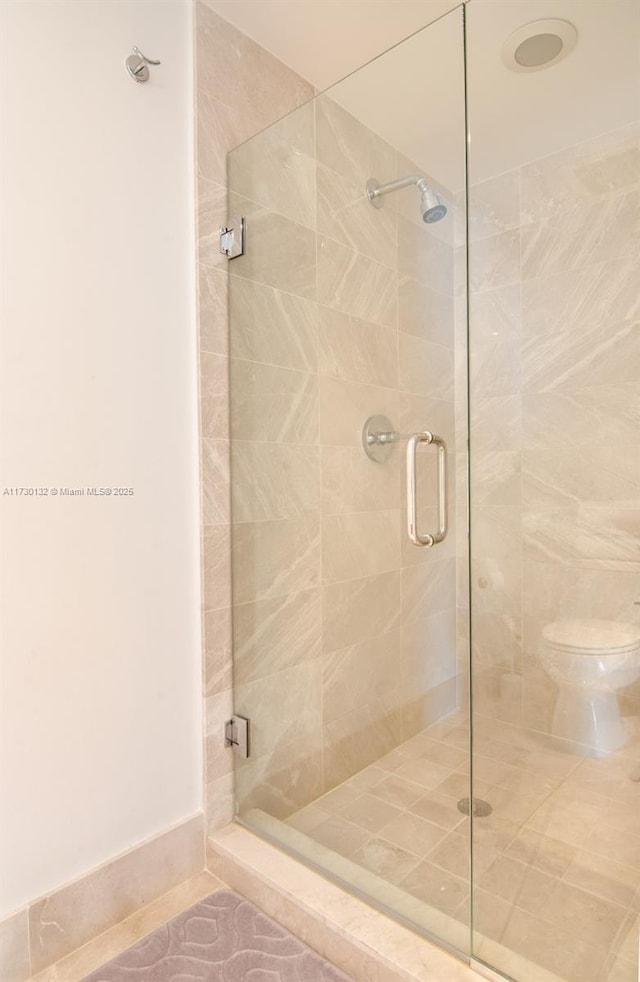 bathroom featuring an enclosed shower, tile patterned floors, and toilet