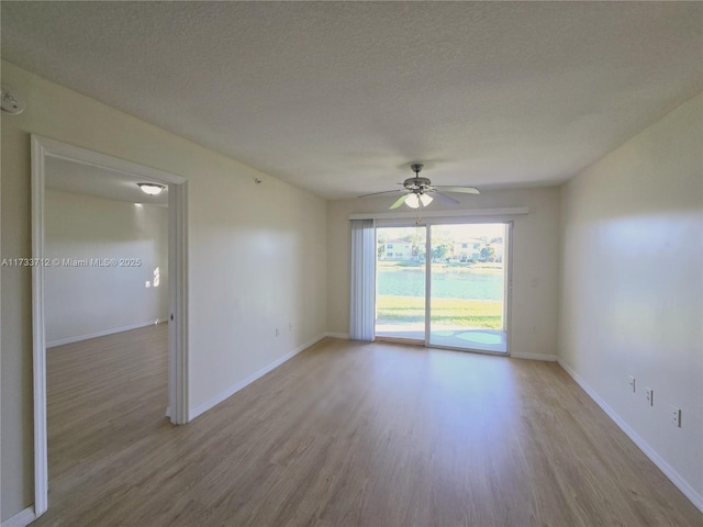 empty room featuring ceiling fan, a textured ceiling, and light wood-type flooring