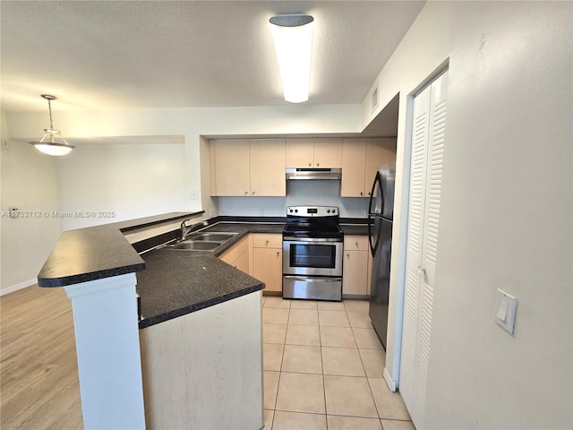 kitchen featuring pendant lighting, sink, stainless steel range with electric stovetop, black fridge, and kitchen peninsula