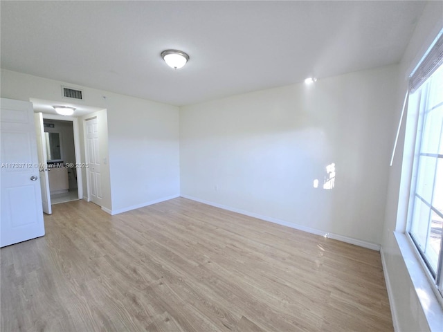 empty room with plenty of natural light and light hardwood / wood-style floors