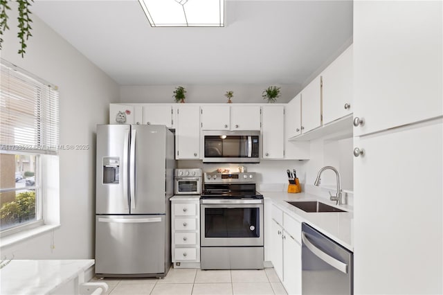 kitchen featuring light tile patterned floors, stainless steel appliances, light countertops, white cabinetry, and a sink