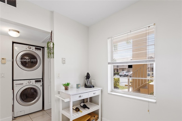 laundry room featuring visible vents, laundry area, light tile patterned flooring, and stacked washer and clothes dryer