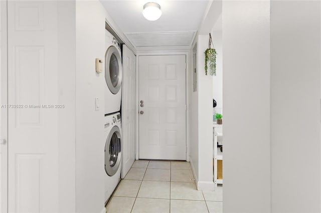 laundry room with laundry area, light tile patterned flooring, and stacked washer and clothes dryer