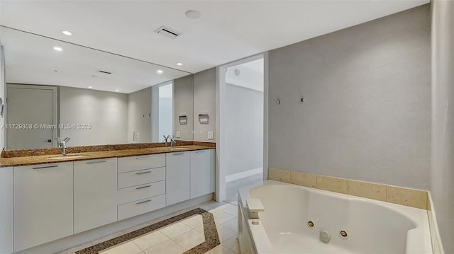 bathroom with a tub to relax in, vanity, and tile patterned floors