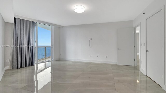 spare room with floor to ceiling windows, a water view, and a wealth of natural light