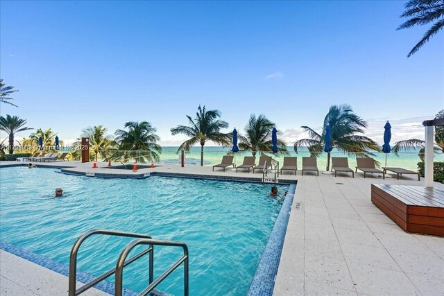 view of swimming pool with a patio area and a water view