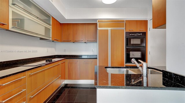 kitchen featuring dark stone countertops, sink, black appliances, and dark tile patterned floors