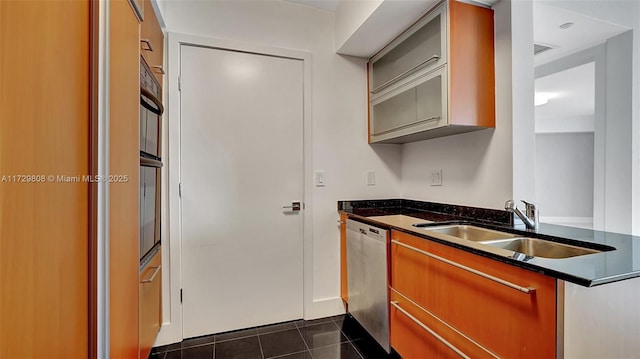 kitchen with stainless steel dishwasher, sink, and dark tile patterned floors