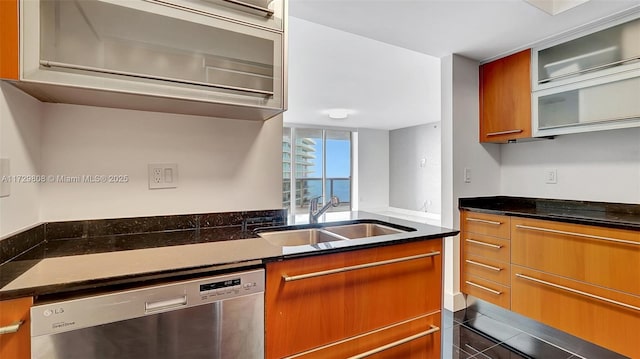 kitchen with stovetop, sink, stainless steel dishwasher, and dark stone counters