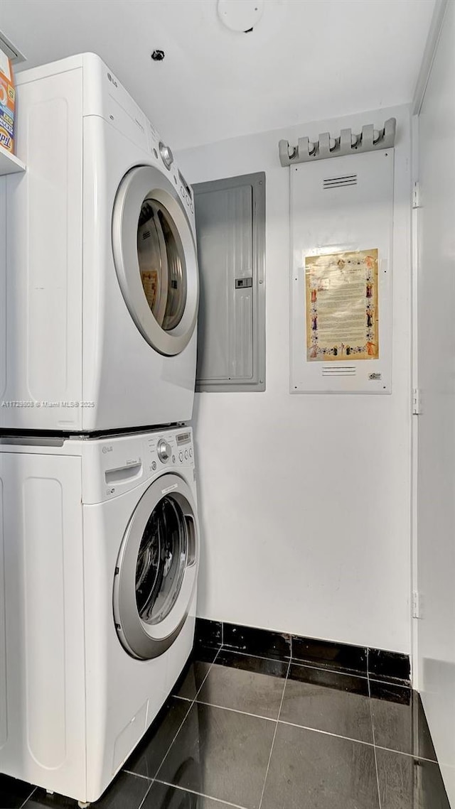laundry area featuring stacked washer and clothes dryer and dark tile patterned floors