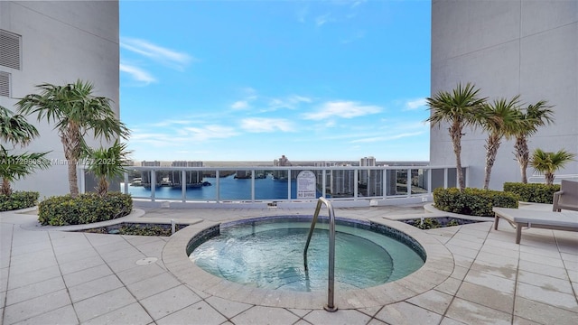 view of pool featuring a community hot tub, a patio, and a water view