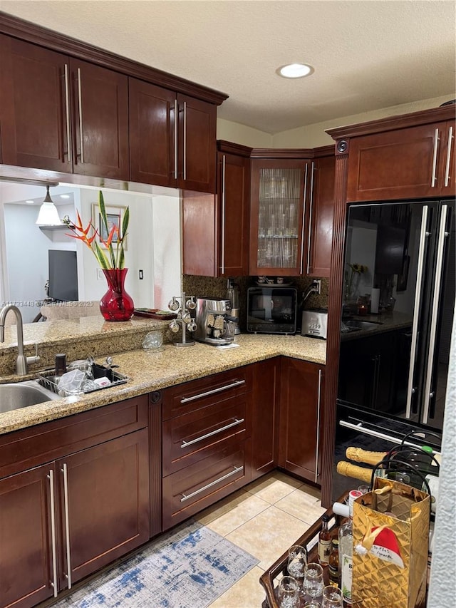 kitchen featuring light tile patterned flooring, sink, light stone counters, and black appliances