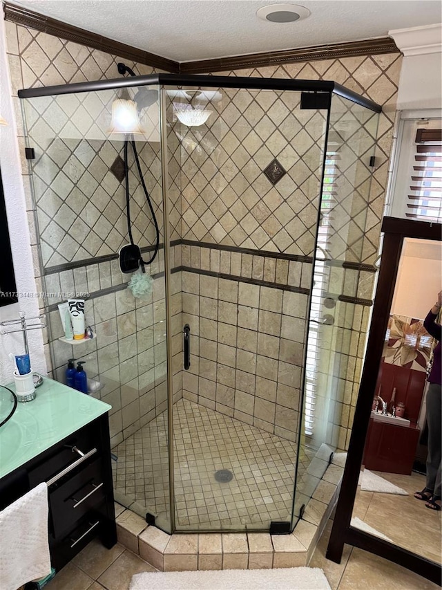 bathroom with a shower with door, crown molding, tile patterned floors, and vanity