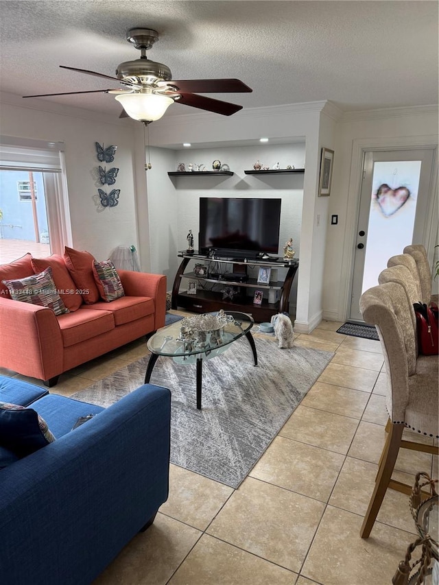 living room featuring ceiling fan, ornamental molding, a textured ceiling, and light tile patterned floors