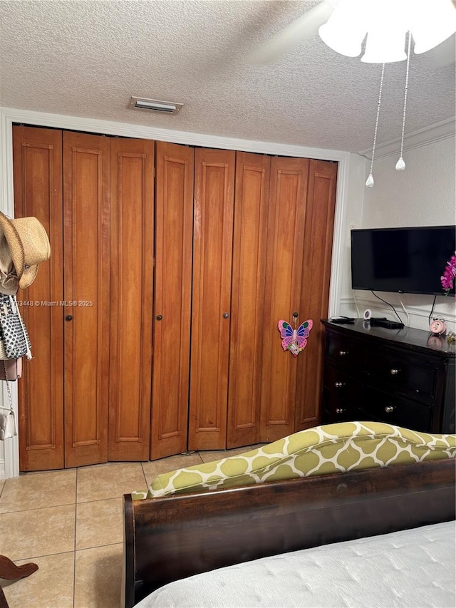 tiled bedroom featuring a textured ceiling and a closet