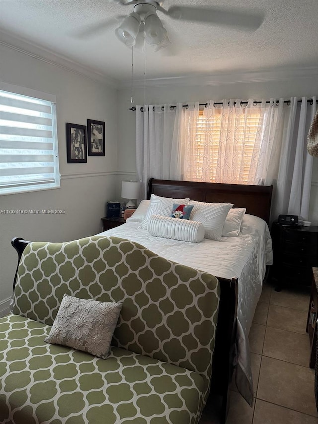 tiled bedroom featuring crown molding, a textured ceiling, and ceiling fan