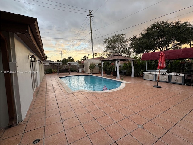 pool at dusk featuring a gazebo, a storage unit, and a patio