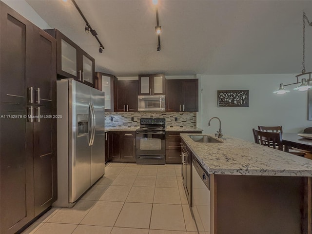 kitchen with sink, light tile patterned floors, stainless steel appliances, a center island with sink, and decorative light fixtures