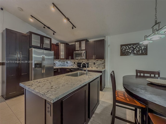 kitchen with appliances with stainless steel finishes, an island with sink, sink, light tile patterned floors, and dark brown cabinets