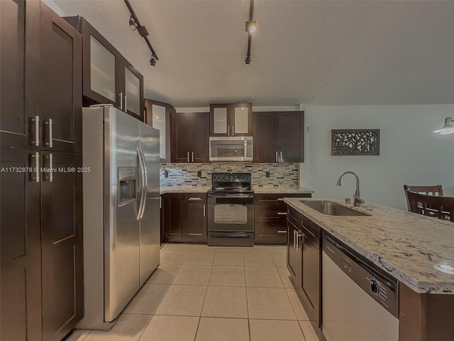 kitchen featuring dark brown cabinetry, sink, tasteful backsplash, light tile patterned floors, and stainless steel appliances