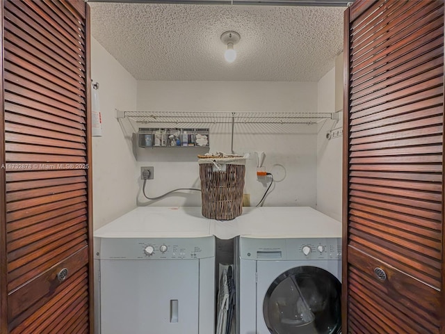 clothes washing area with washing machine and dryer and a textured ceiling