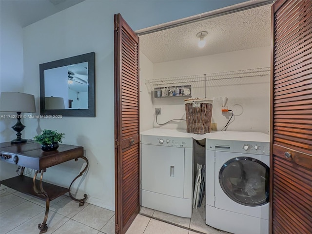 washroom with washing machine and dryer, light tile patterned flooring, and a textured ceiling