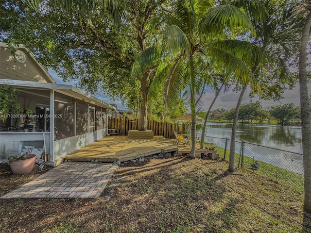 view of yard featuring a deck with water view and a sunroom