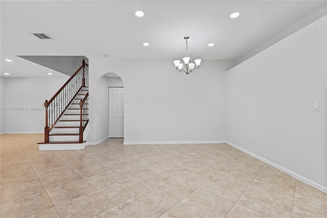 tiled empty room featuring a chandelier