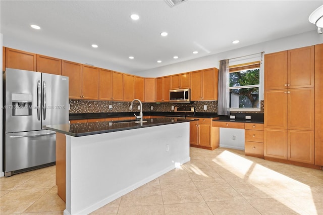 kitchen featuring sink, light tile patterned floors, stainless steel appliances, and an island with sink