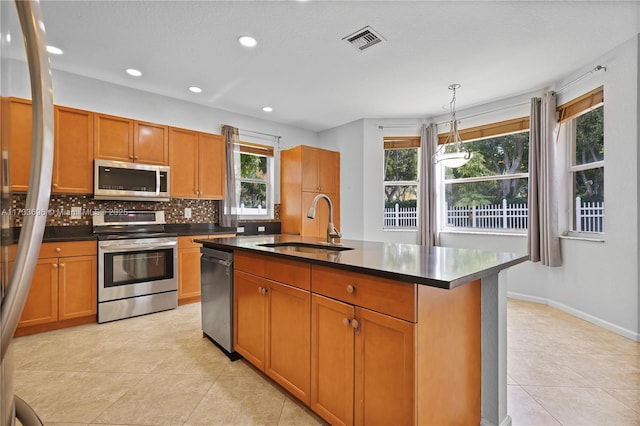 kitchen with a healthy amount of sunlight, appliances with stainless steel finishes, sink, and a center island with sink