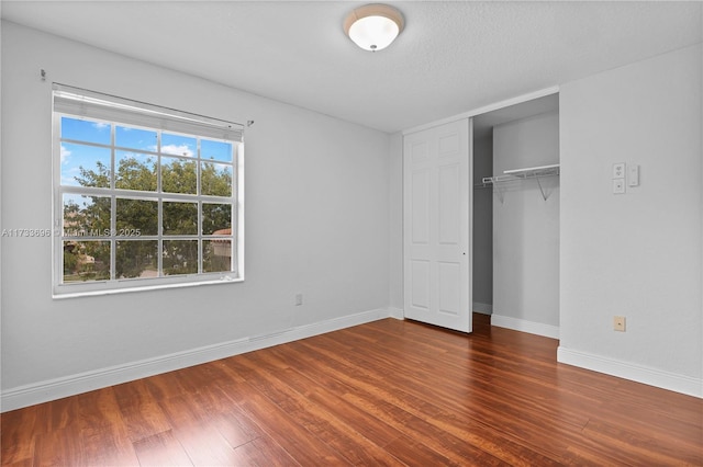 unfurnished bedroom featuring dark hardwood / wood-style flooring and a closet