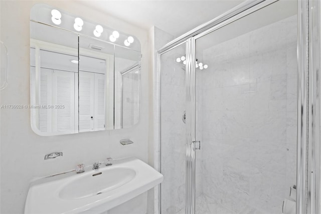 bathroom featuring a shower with door and sink