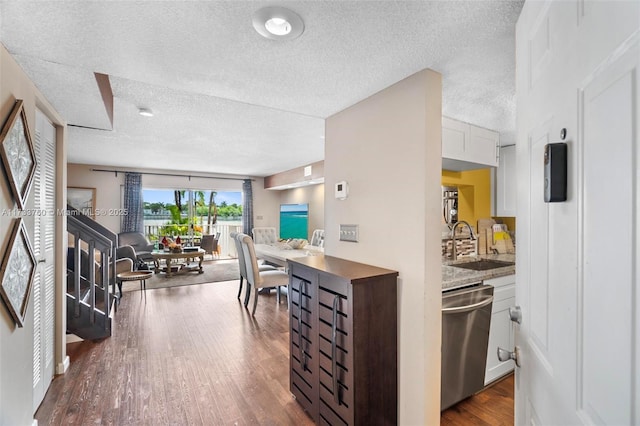 kitchen featuring sink, dark hardwood / wood-style floors, a textured ceiling, white cabinets, and stainless steel dishwasher